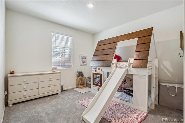 Child's bedroom with a white loft bed and slide and a house-shaped wooden frame.
