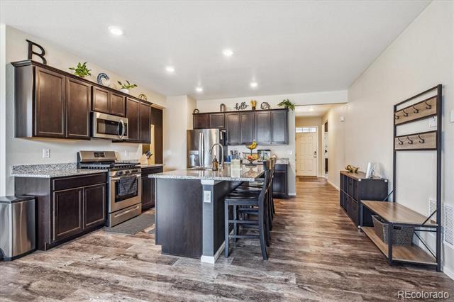 Open kitchen with dark cabinets, stainless steel appliances, and a large island with seating.