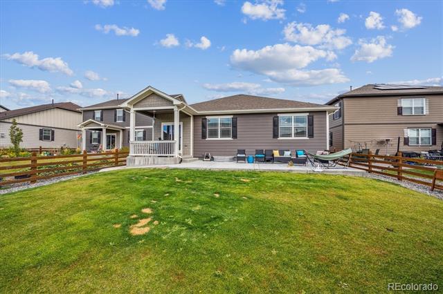 Gray home with a covered back porch, patio seating, and a fenced lawn.