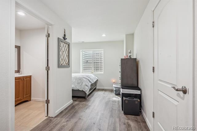 Bedroom with a bed beneath a shuttered window and a dark dresser beside the hallway doorway.