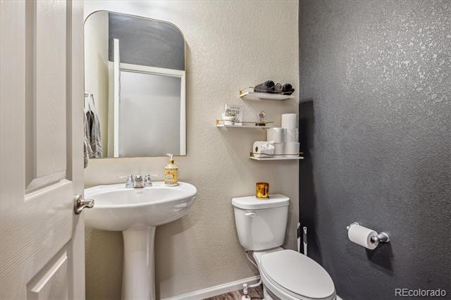 Bathroom with a pedestal sink, toilet, and dark charcoal accent wall.