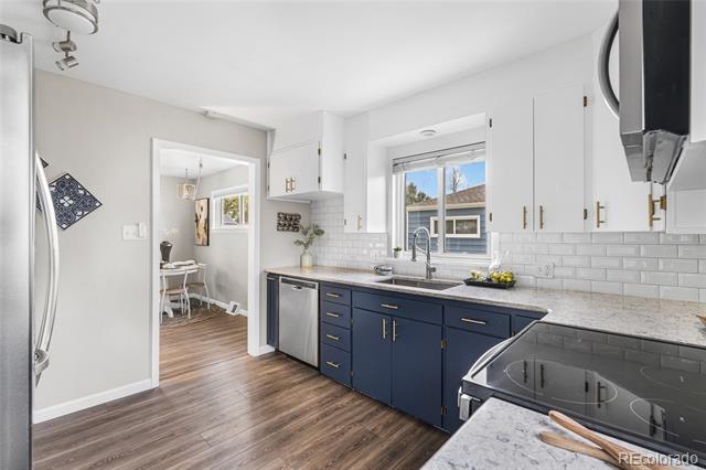 Kitchen with navy-blue cabinets, white tile backsplash, and a window above the sink.