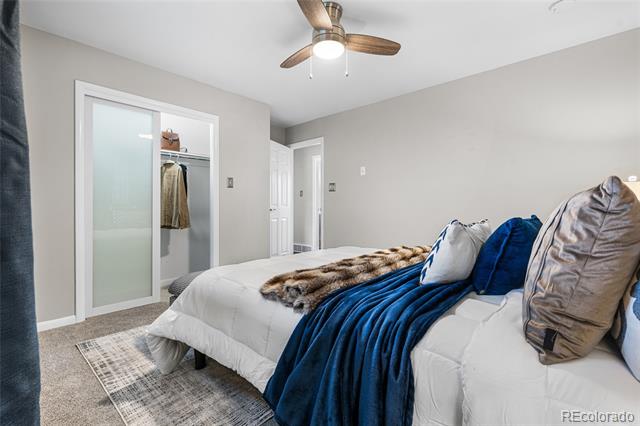 Staged bedroom with a white bed, blue throw blanket, and sliding closet doors.
