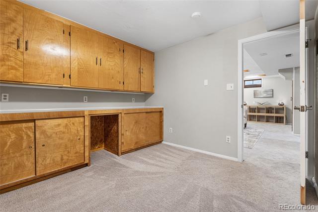 Carpeted room with extensive honey-colored built-in cabinets and an open doorway to the living area.