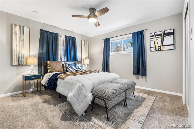 Staged bedroom with white bedding, navy curtains, and an upholstered bench at the foot of the bed.