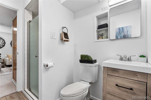 Bathroom with a glass shower, white toilet, and wood-front vanity.