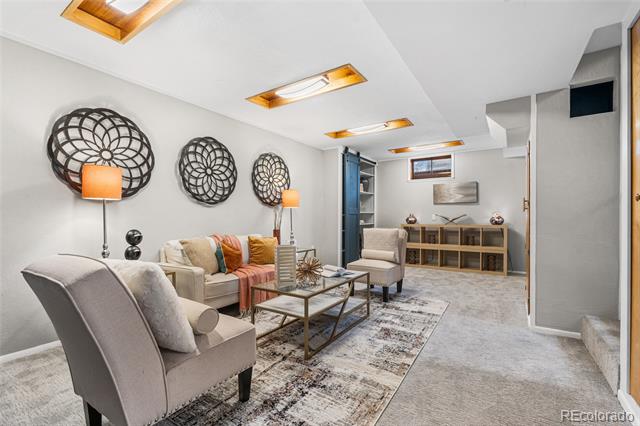 Furnished living room with a light sofa, armchairs, glass coffee tables, and recessed ceiling lights.