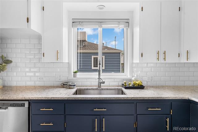 Kitchen with navy lower cabinets, white subway tile, and a sink beneath a window.