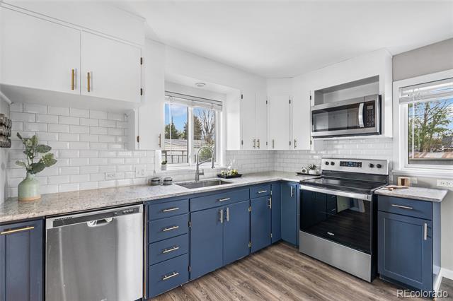 Renovated kitchen with navy lower cabinets, white subway-tile backsplash, and stainless-steel appliances.