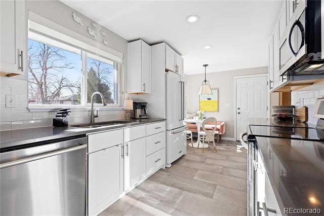 Bright kitchen with white cabinets, stainless steel appliances, and a small dining area by the window.