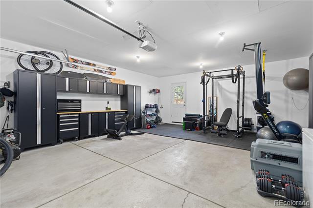 Garage home gym with dark built-in cabinets, exercise equipment, and a wide concrete floor.