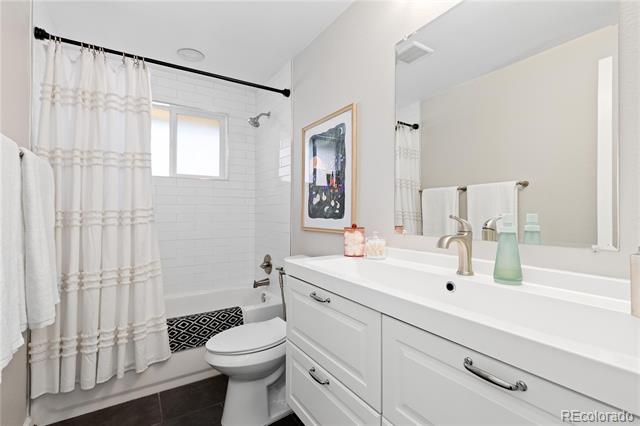 Bathroom with a white double-sink vanity, large mirror, and subway-tile shower with a small window.