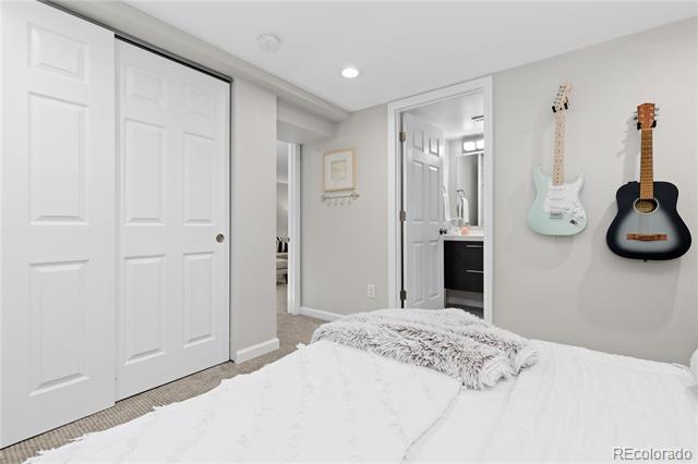 Bedroom with two wall-mounted guitars, a white bed, and sliding closet doors.