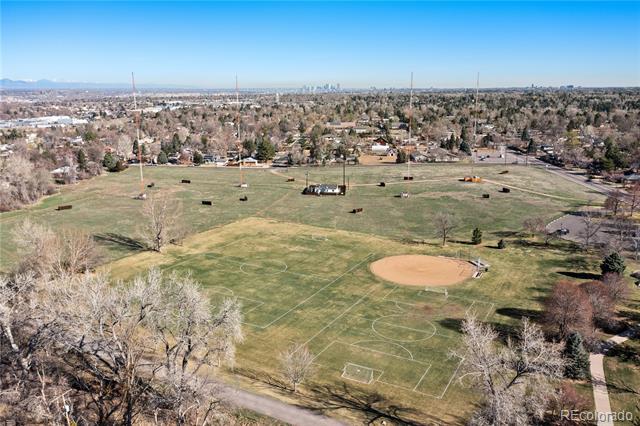 Aerial view of soccer fields and a baseball diamond, with homes and a distant skyline.