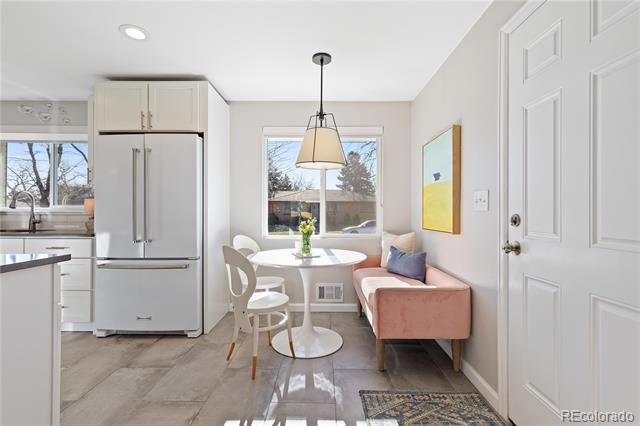 Kitchen breakfast nook with a round table, pink bench, and stainless steel refrigerator.