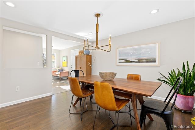 Dining room with a long wooden table, mixed chairs, and a brass chandelier.
