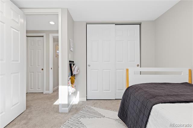 Bedroom with a dark gray quilt, white paneled closet doors, and an open doorway to the hall.