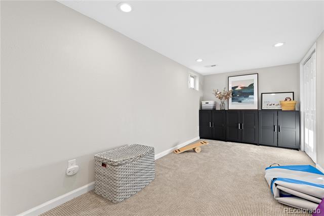 Carpeted basement room with black storage cabinets, a woven hamper, and toys.