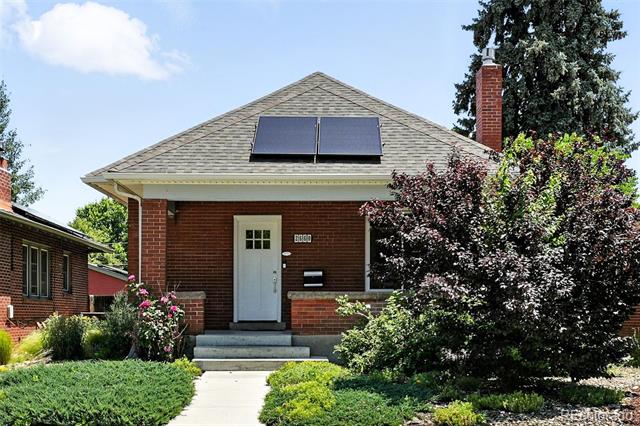 Brick house with solar panels, a white entry door, and landscaped front garden.