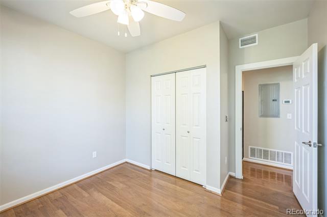 Vacant bedroom with hardwood floors, a ceiling fan, and double closet doors.