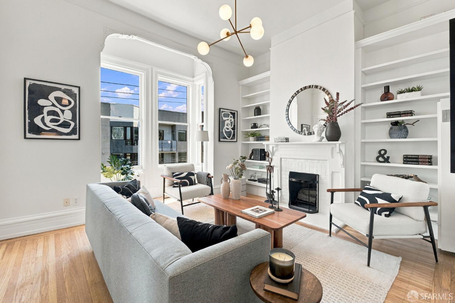 Living room with tall bay windows, a white fireplace, built-in shelves, and contemporary furnishings.