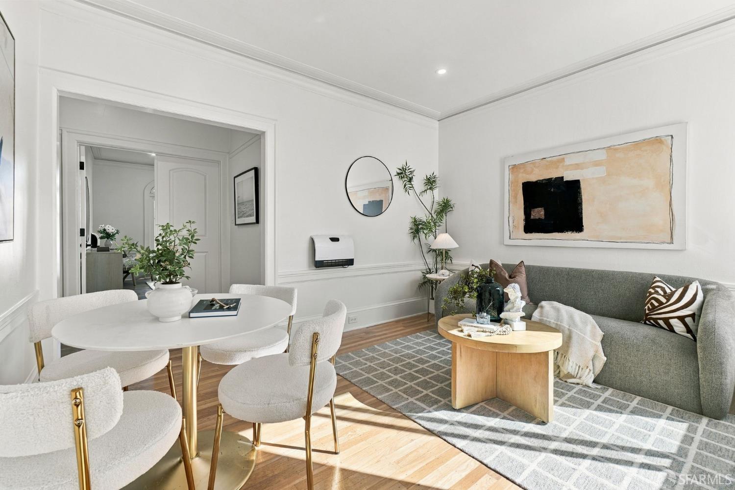 Staged living and dining room with a gray sofa, round dining table, and geometric rug.