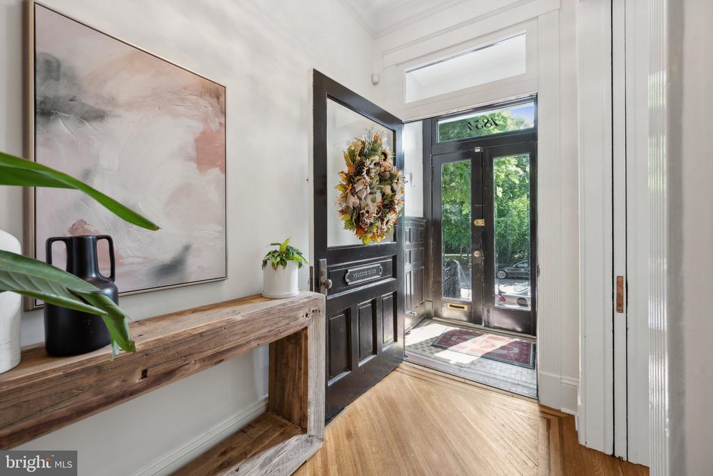 Furnished entryway with an open black door, rustic console table, and abstract wall art.