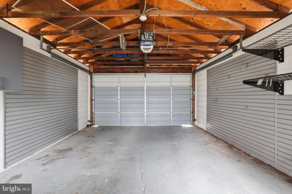 Empty garage with exposed wooden roof framing, gray storage panels, and a closed sectional door.