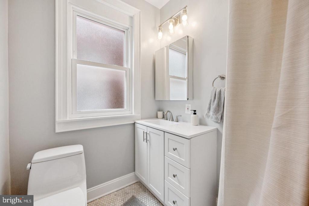 Bathroom with white vanity, frosted window, and hexagonal tile floor.