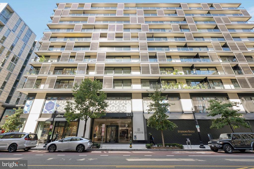 Modern high-rise condominium with stacked balconies and ground-floor storefronts on H Street.