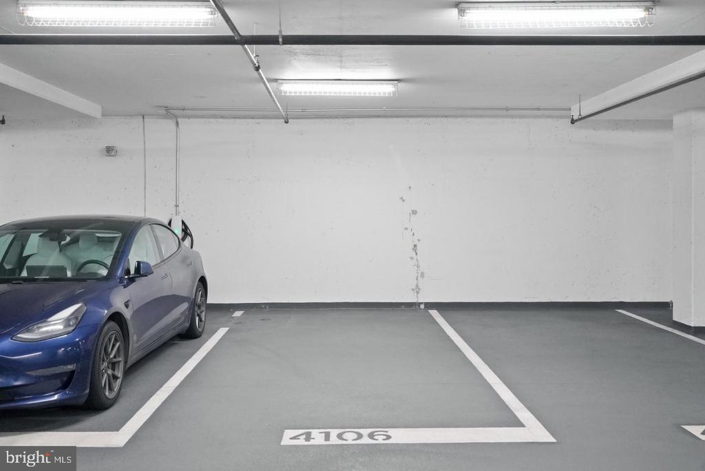 Parking garage space 4106 beside a blue car, with fluorescent lights overhead.