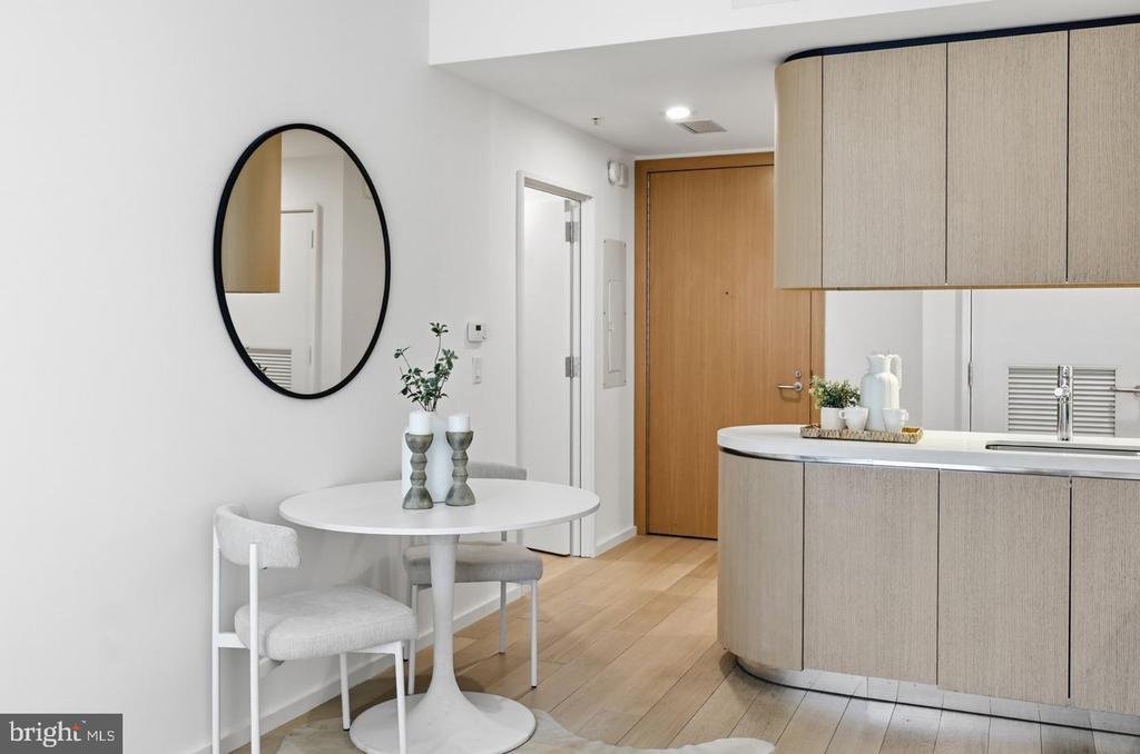 Open-plan condo kitchen with a curved island and a small dining table beneath an oval mirror.