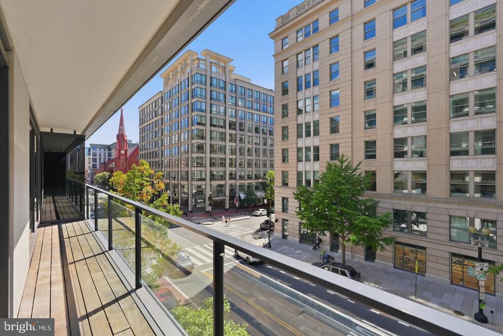 Apartment balcony overlooking a downtown street, office buildings, and a red brick church.