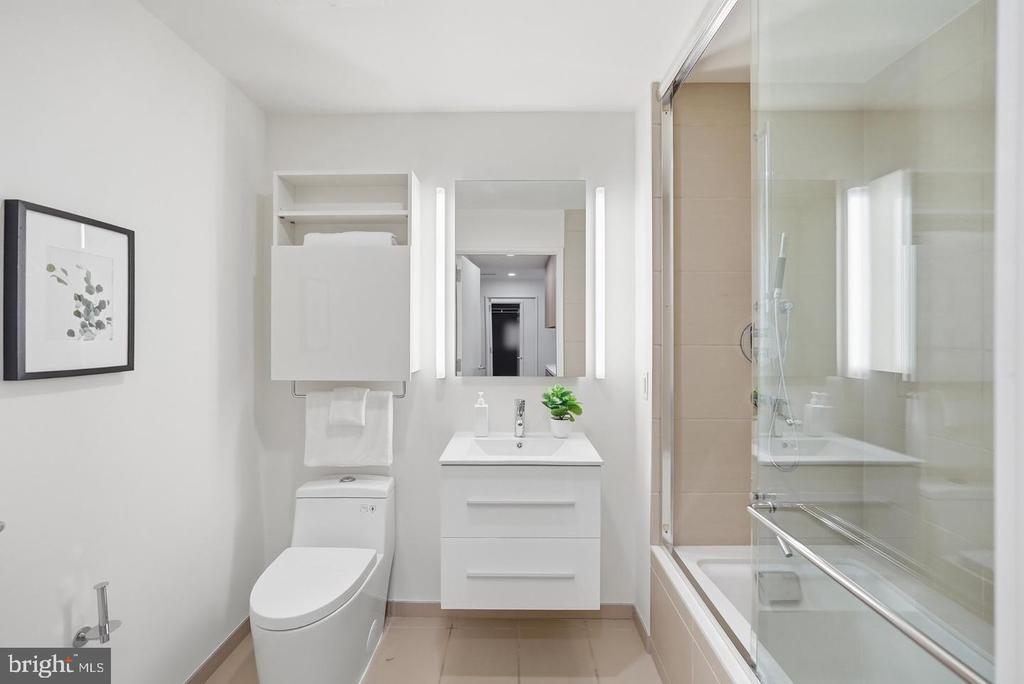 Modern bathroom with a floating vanity and glass-enclosed bathtub and shower.
