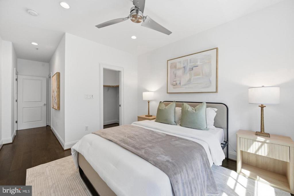 Staged bedroom with a white bed, pale green pillows, gray throw, and ceiling fan.