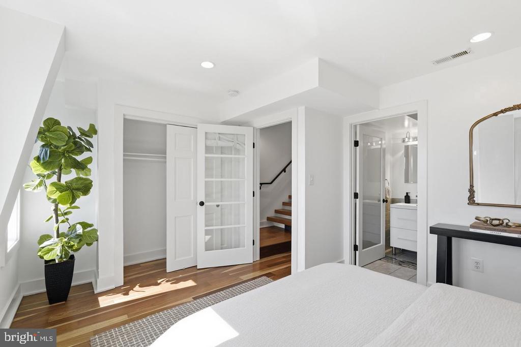 Bedroom with hardwood floors, open closet doors, and an adjoining bathroom.