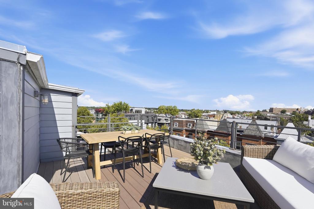 Rooftop deck with dining and lounge seating overlooking Washington, DC rooftops.