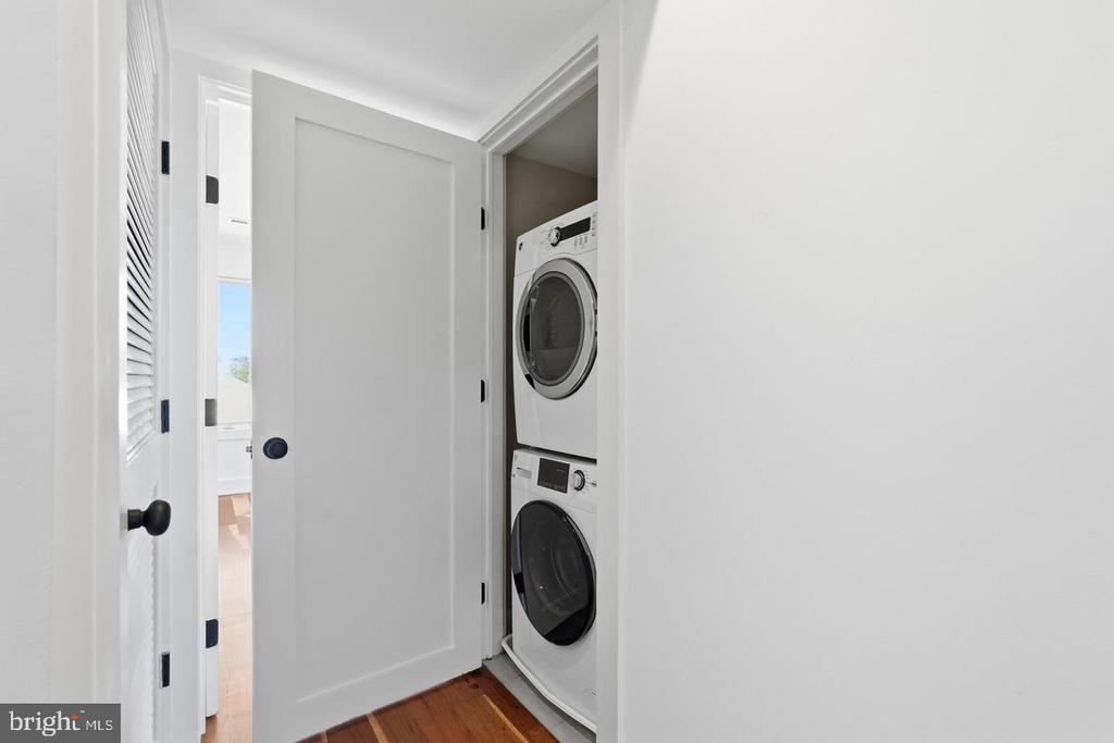 Laundry closet with a stacked washer and dryer behind an open door.
