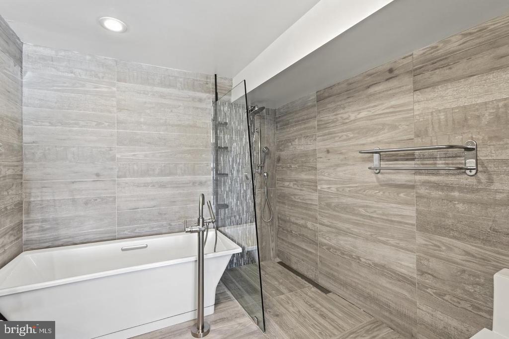 Bathroom with a freestanding soaking tub, glass walk-in shower, and gray wood-look tile.