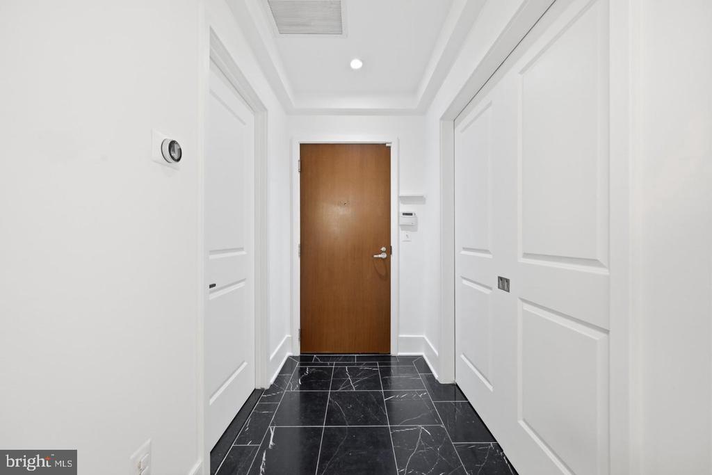 Entry hallway with a brown front door and black marble-look tile flooring.