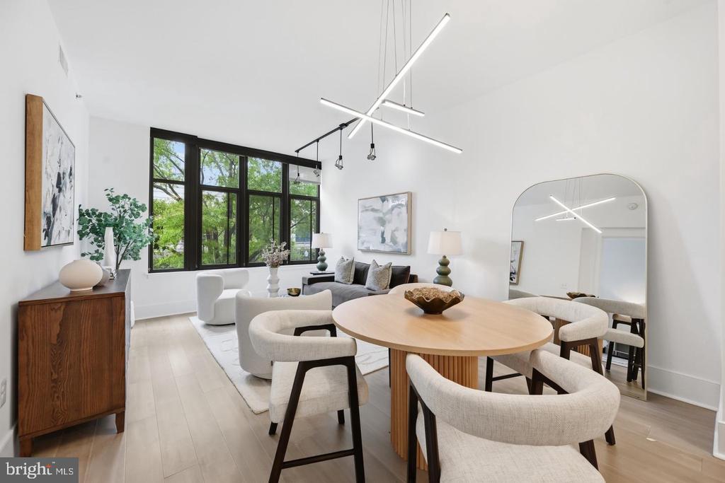Open dining and living area with a round wood table, black-framed windows, and contemporary furnishings.