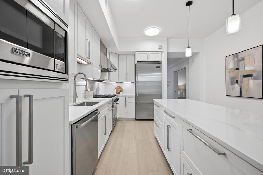 Modern apartment kitchen with white cabinetry, a long island, and stainless steel appliances.