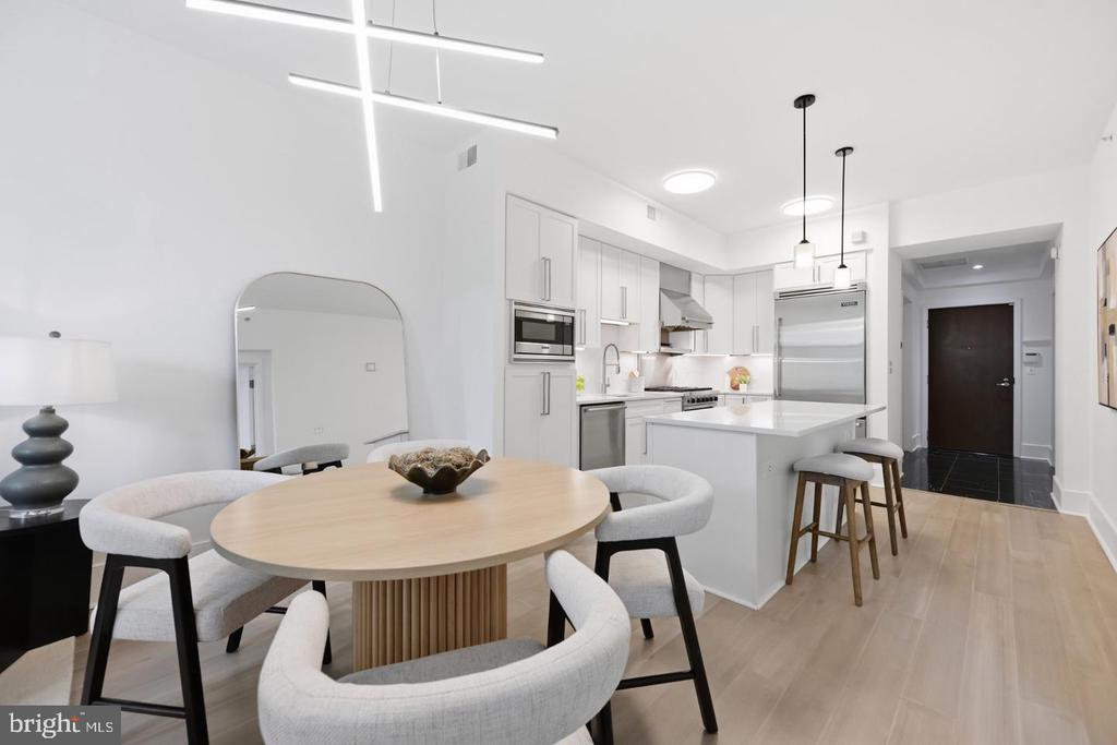 Open-plan kitchen and dining area with a white island, stainless appliances, and round wood table.