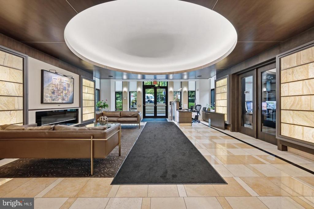 Building lobby with tan leather seating, marble floors, and a large circular ceiling feature.