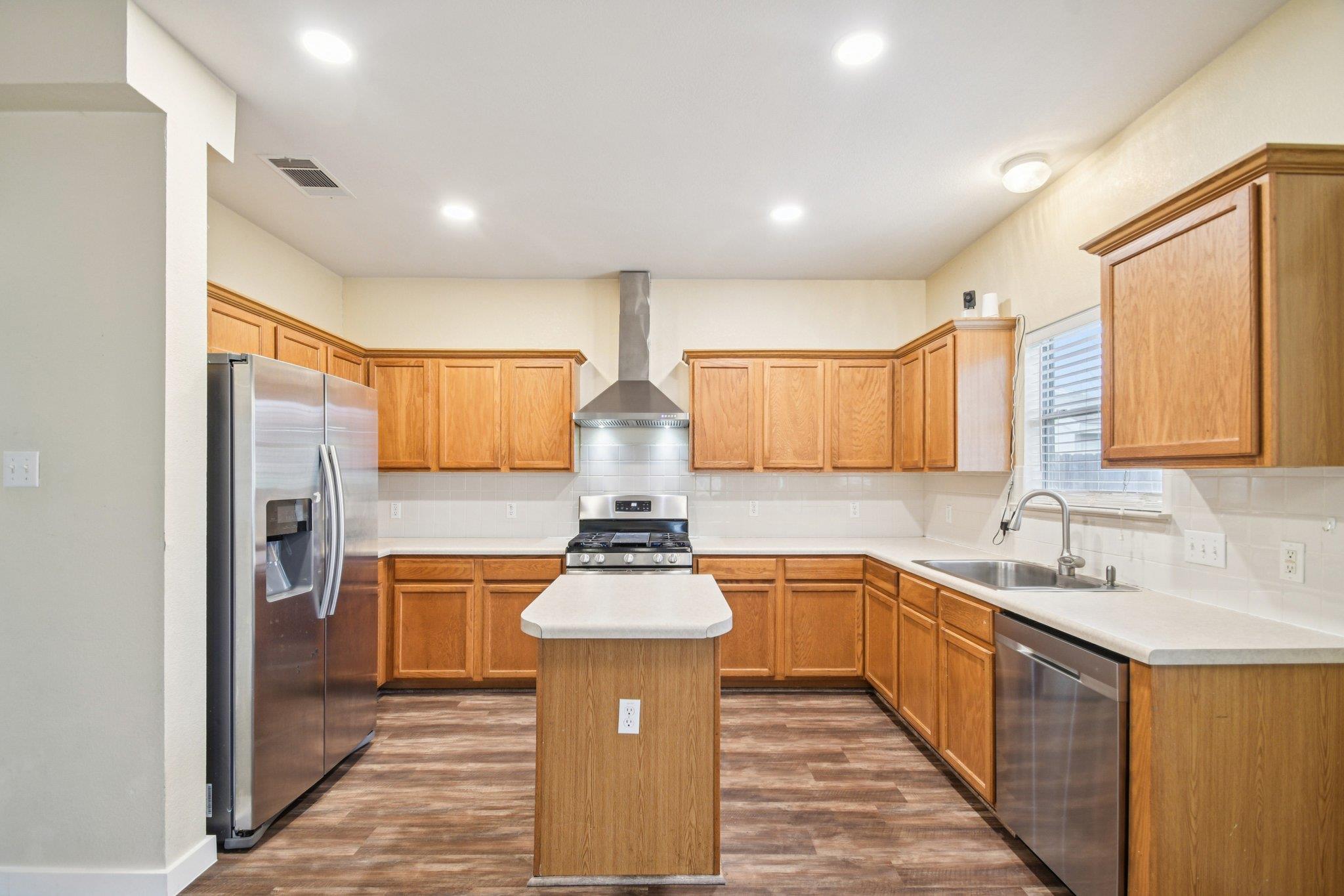Kitchen with warm wood cabinets, a central island, and stainless steel appliances.