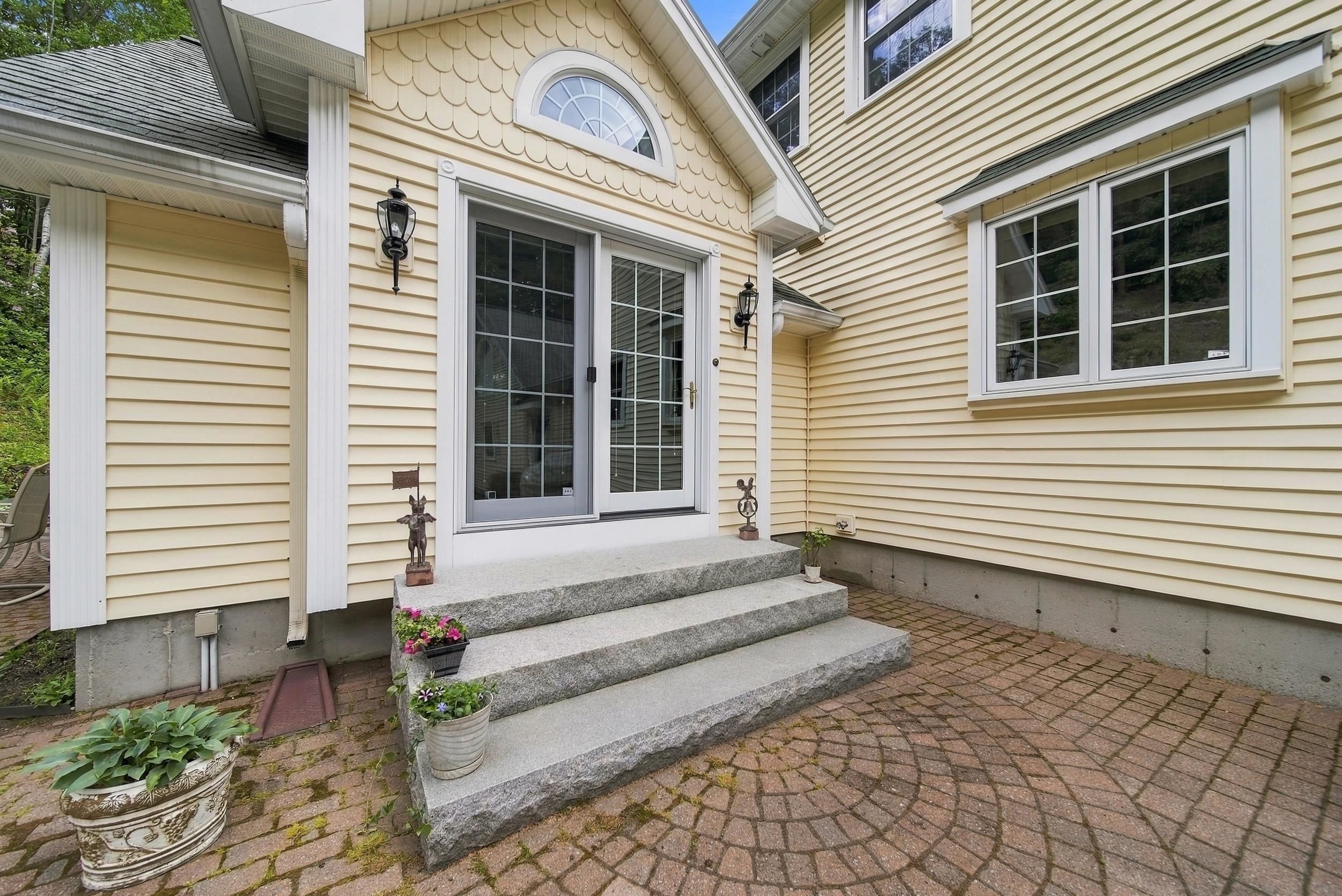 House entry with arched window, granite steps, and a curved brick-paver walkway.
