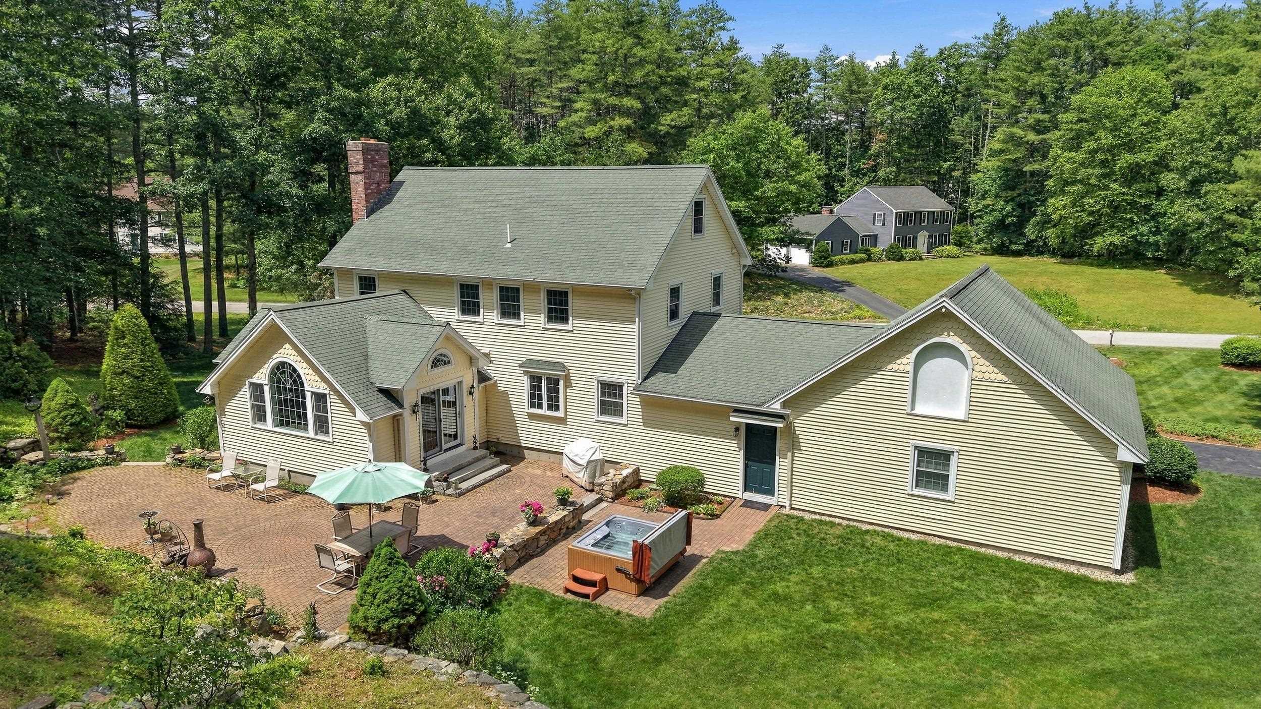 Elevated view of a cream-sided home with a brick patio, outdoor seating, and a hot tub.