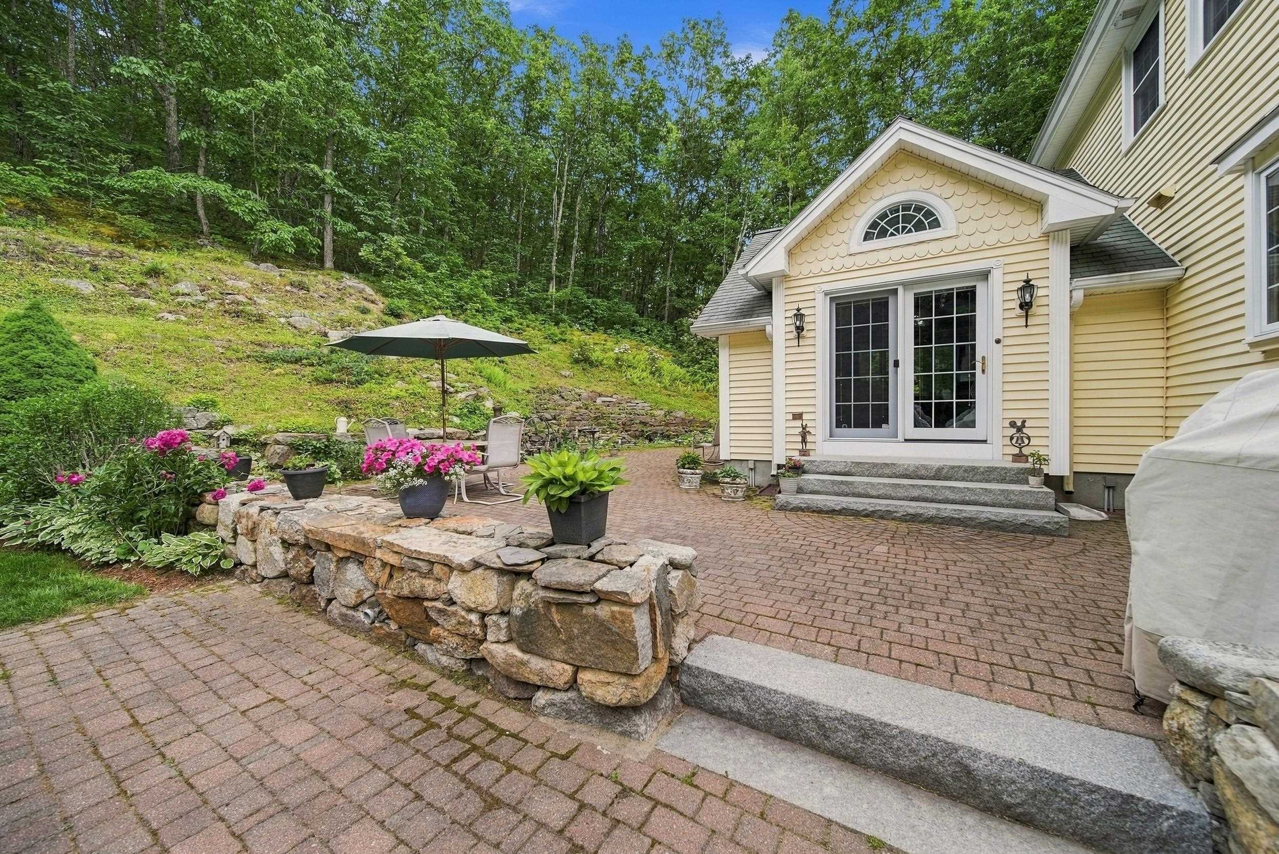 Cream-colored home with French doors opening onto a brick patio and stone garden wall.