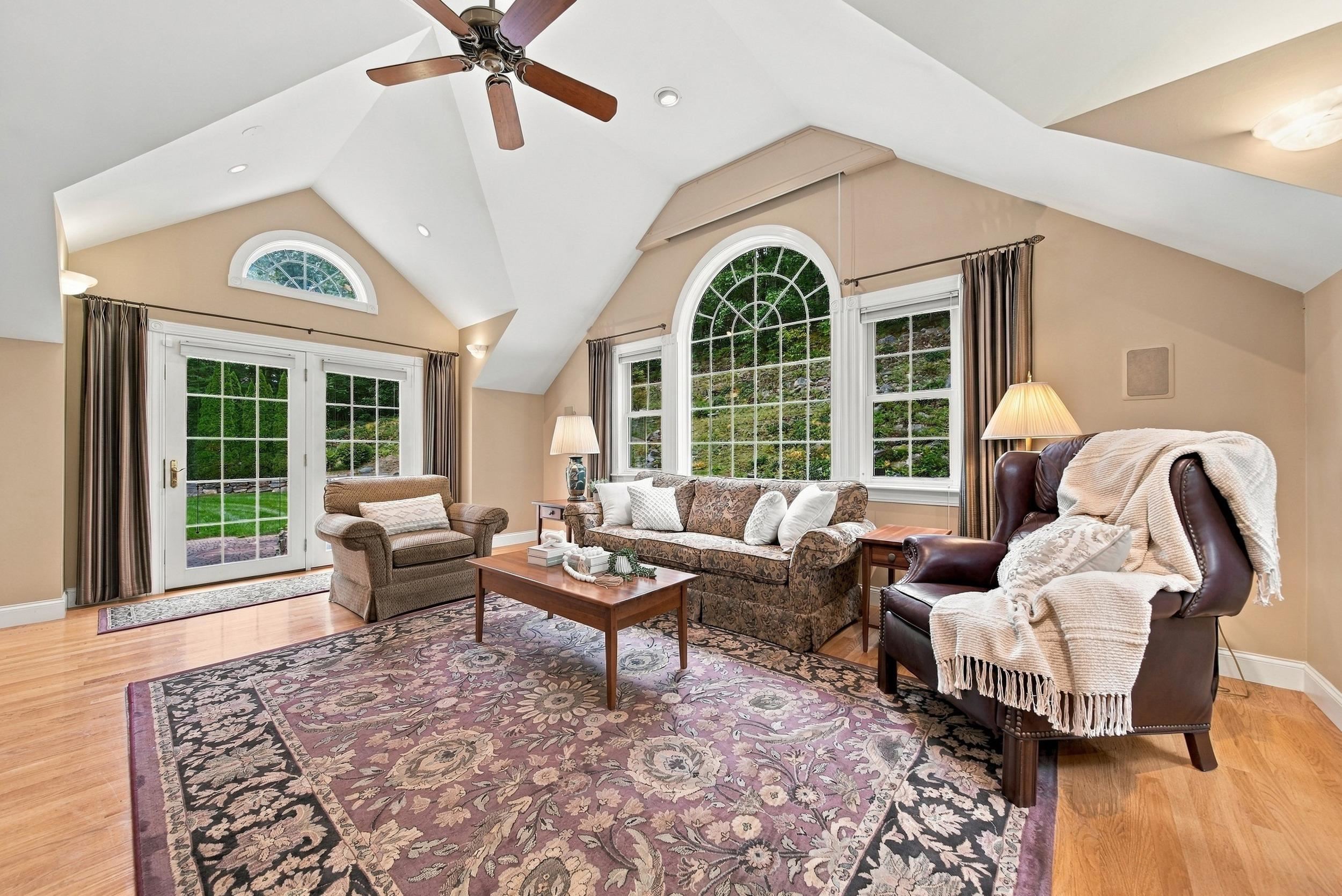 Living room with vaulted ceiling, arched windows, French doors, and patterned rug.