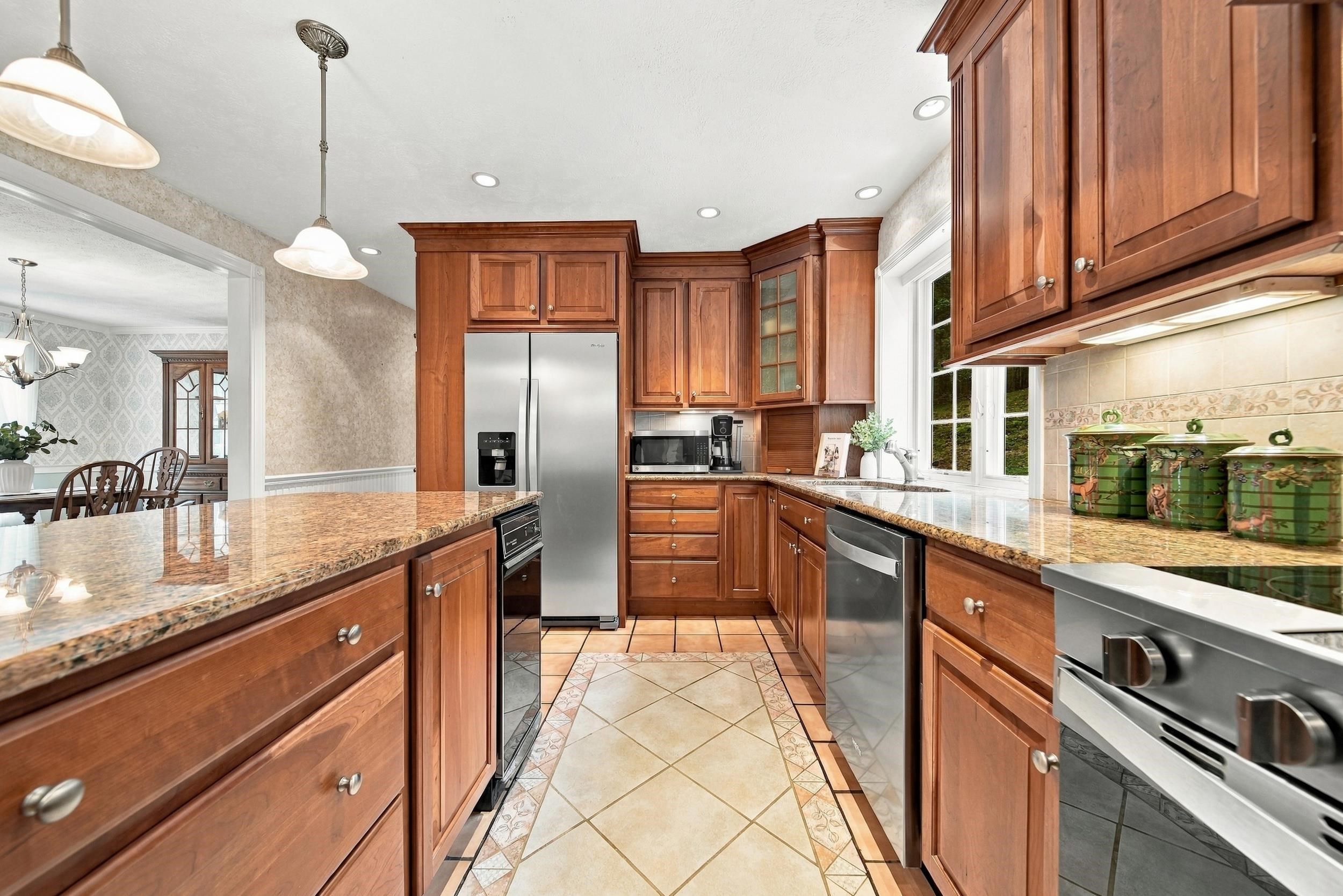 Kitchen with wood cabinets, granite counters, stainless steel appliances, and a tiled floor.